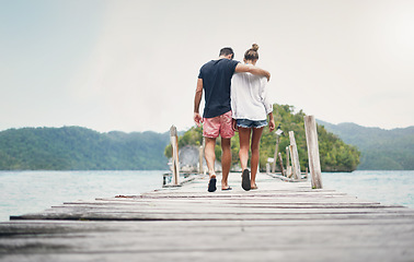 Image showing Couple, vacation and walking on ocean boardwalk for travel, freedom and peace. Back of a man and woman hug and walk to relax on Indonesia holiday, tropical adventure or nature date at sea on a deck