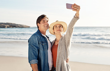 Image showing Young couple, beach selfie and happy in summer sunshine for love, romance or smile for social media post. Man, woman and profile picture for blog, app or internet by ocean, waves or sea for holiday
