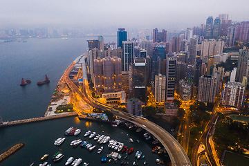 Image showing Buildings, ocean and aerial view of the city at night with lights, boats and ships on the sea harbor. Landscape, architecture and drone of an urban town with skyscrapers, yachts and infrastructure.