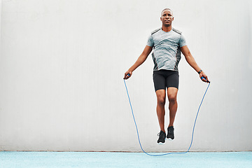 Image showing Jump, rope and training with black man skipping in stadium for sports, workout practice and cardio. Health and body with athlete jumping on track for strong, mockup space and exercise against wall