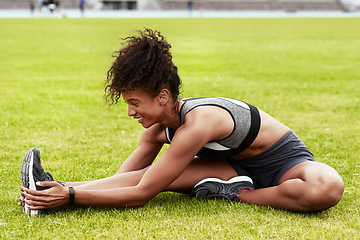 Image showing Happy woman, athlete and stretching body on grass for running, exercise or workout at the stadium. Active female person in warm up leg stretch for fitness, sports training or cardio run on the field