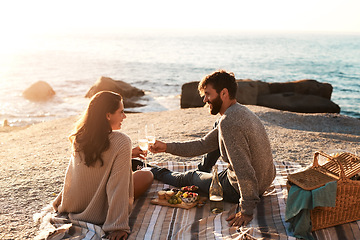 Image showing Picnic, beach and couple with champagne happy for relax, bonding and quality time on romantic date. Nature, dating and man and woman toast for anniversary, honeymoon and love on holiday or vacation