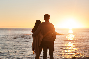 Image showing Sunset, beach and back of couple hug in evening on holiday, summer vacation and weekend by ocean. Nature, love and man and woman embrace, hugging and relax for bonding, quality time and peace by sea