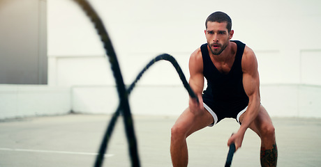 Image showing Man, fitness and battle ropes in training, exercise or workout for physical wellness outdoors. Fit, active and serious male person exercising with rope for intense body endurance, stamina or cardio