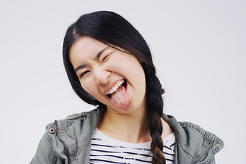 Image showing Portrait, funny face and tongue with an asian woman in studio on a white background looking silly or goofy. Comedy, comic and wink with a crazy young female person joking indoor for fun or humor