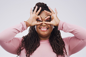 Image showing Portrait, funny face and finger mask with a black woman laughing in studio on a white background for humor. Comic, comedy and hands as glasses with a playful young female person joking or having fun