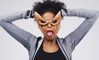 Image showing Portrait, funny face and finger glasses with an african woman in studio on a gray background looking silly or goofy. Comedy, comic and mask with a crazy young female person joking for fun or humor