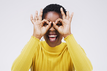 Image showing Portrait, funny face and finger glasses with a black woman laughing in studio on a white background for humor. Comic, comedy and hands on eyes with a playful young female person joking or having fun