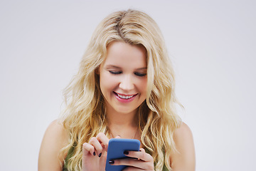 Image showing Smile, social media and woman with a smartphone, typing and communication against a grey studio background. Female person, girl and model with a cellphone, network and online reading with happiness