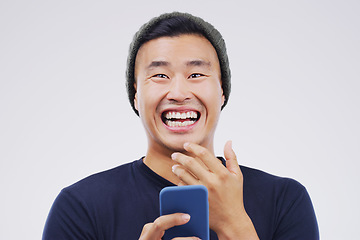 Image showing Comic, portrait and Asian man with a smartphone, funny and happiness against a grey studio background. Face, male person and guy with a cellphone, mobile app and meme with a smile, joy and connection