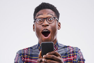 Image showing Black man, surprise and phone in shock for winning, prize or good news against a white studio background. Shocked or surprised African male person with mobile smartphone, wow or lottery competition