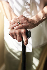 Image showing Hands, walking stick and closeup with elderly woman, injury and mobility with balance in retirement in house. Cane, senior lady and person with disability, support or recovery in home with lens flare