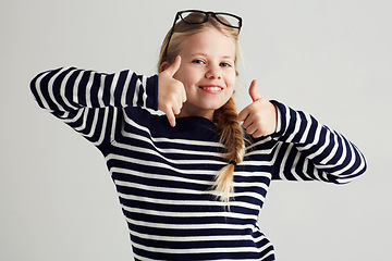 Image showing Thank you, thumbs up and portrait of young girl or child doing yes, celebrate or happy sign with hand. Glasses, agree and female kid or person smile and like gesture in a grey studio background