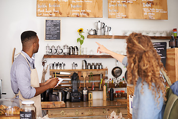 Image showing Woman, cafe and pointing at menu on wall with barista, notes and decision for good customer experience. Male waiter writing, lady and talking with choice, thinking and order special from bakery shop