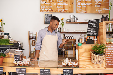 Image showing Black man, coffee shop and store phone of an entrepreneur with happiness from small business. Cafe, mobile and barista looking at online app with a smile at bakery and restaurant feeling happy