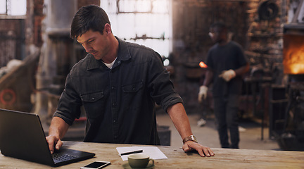 Image showing Workshop, man and working on laptop in metal blacksmith factory for trade business, finance and industry technology. Welder, computer and online paperwork for businessman, staff and forge worker
