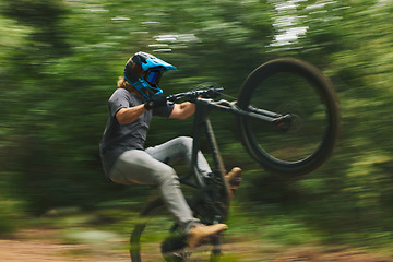 Image showing Fitness, trail and man doing a trick on a bike while riding for competition practice in the woods. Extreme sports, blur motion and male athlete biker with skill training or exercise in outdoor forest