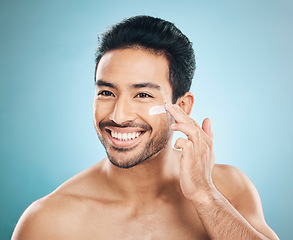 Image showing Skincare, beauty and man with face cream in a studio for a natural, wellness and health routine. Happy male model with facial spf, lotion or moisturizer for dermatology treatment by a blue background