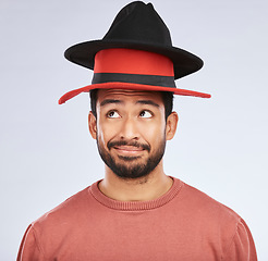 Image showing Confused, hats and young man in a studio with a thinking, idea or contemplating face expression. Pensive, thoughtful and Indian male person with fun head accessories isolated by a white background.