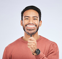 Image showing Portrait, teeth and man with a magnifying glass, smile and search against a studio background. Face, male person and model with a tool, zoom and happiness with oral health, dental hygiene and care