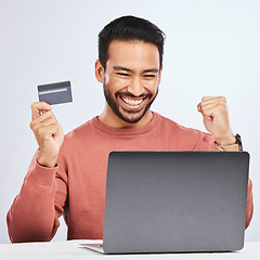 Image showing Excited man, laptop and credit card for online shopping, e commerce and payment in studio. Asian male person with technology and hand to celebrate savings, promotion or sale on a fintech website