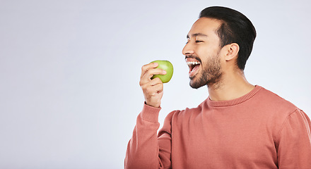 Image showing Green apple, eating and happy man isolated on a white background for healthy food, diet and detox space. Vegan person, nutritionist or asian model with fruit for self care or lose weight in studio