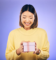 Image showing Happy, smile and woman with a gift box in a studio for a birthday, achievement or celebration. Happiness, excited and Asian female model with a present package for party isolated by purple background