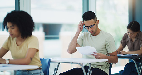 Image showing Thinking, man and education test in a classroom with writing and student learning at a university. College exam, school and male person planning with document in a lecture hall with stress and paper