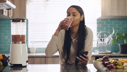 Image showing Smoothie, phone and woman in kitchen for breakfast, texting and healthy diet in her home. Fruit, shake and female health influencer with smartphone app for social media, blog or vlog for vegan recipe