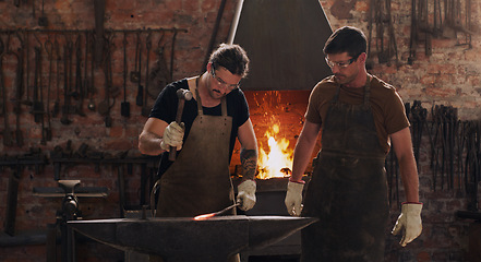 Image showing Hammer, anvil and fire with men working in a forge for metal work manufacturing or production. Industry, welding and trade with blacksmith professionals in a workshop, plant or industrial foundry