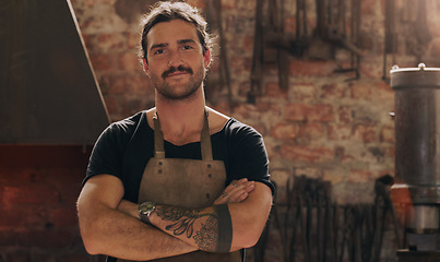 Image showing Portrait, industry and a man arms crossed in a workshop for metal work, engineering or construction. Manufacturing, production and a confident young male industrial blacksmith in a factory or plant