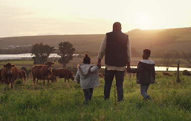 Image showing Family, holding hands and a father walking on a farm with children for agriculture or sustainability. Back, farming and a dad with his kids in the meadow as a cow farmer in the countryside at sunset