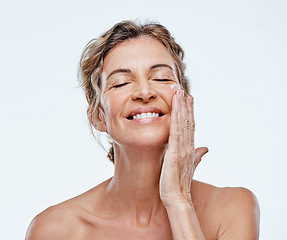 Image showing Skincare, smile and a woman with an anti aging cream isolated on a white background in a studio. Happy, moisturize and a mature model with facial lotion for beauty, wellness and care of skin