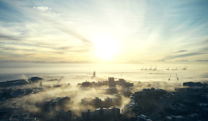 Image showing City, sea and sunrise landscape with building skyline and ocean background in Cape Town. Fog, clouds and drone of sky with urban cityscape and sunlight outdoor in the morning by water and buildings