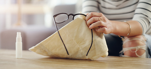 Image showing Hand, closeup of woman cleaning glasses and spray bottle with chemical liquid, fabric cloth and hygiene. Clean spectacles, eyewear and female cleaner at home with eye care with lens maintenance