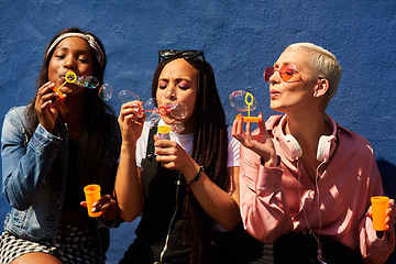 Image showing Bubbles women and diverse friends on summer vacation, holiday travel or bonding activity and against a blue wall. Happy, game and ladies playing with soap or wand toy or in freedom and social break