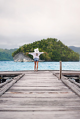 Image showing Island, ocean and woman with freedom on boardwalk for holiday, summer vacation and weekend in Maldives. Travel, tropical sea and female person on luxury resort for carefree, happiness and relaxing