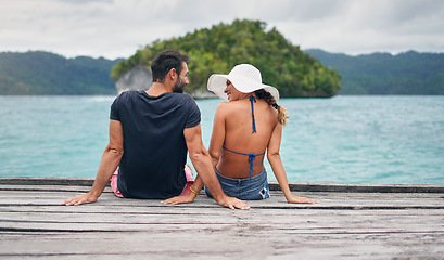 Image showing Vacation, ocean and back of couple together on deck, dock or sitting on boardwalk to relax and enjoy the sea, water or landscape. People, man and woman on holiday, summer travel or date in nature