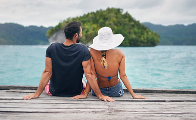 Image showing Back, couple and vacation together on ocean deck, dock or sitting on boardwalk to relax or enjoy the sea or water landscape. People, man and woman on holiday, summer travel or date in tropical nature