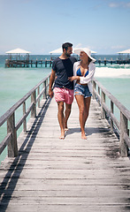 Image showing Happy couple, tropical and ocean boardwalk with walk, hug and outdoor in summer sunshine for holiday. Man, woman and walking together by sea with love, happiness and talking with travel for vacation