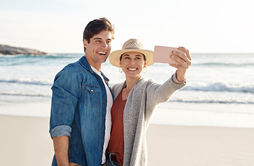 Image showing Young couple, beach selfie and smile in summer sunshine for love, romance or happy for social media post. Man, woman and profile picture for blog, app or internet by ocean, waves or sea for vacation