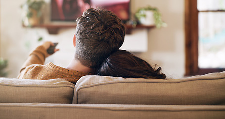 Image showing Watching tv, couple and love in a home on a living room sofa with bonding feeling relax. Cuddle, lounge couch and house with a television and movie with people back streaming series with remote