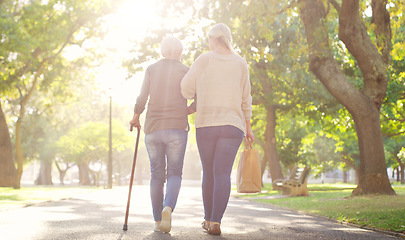 Image showing Walking, park and and woman with elderly mother for bonding, assistance and help outdoors. Nature, family and female person with disability with cane and adult daughter for wellness, relax or support