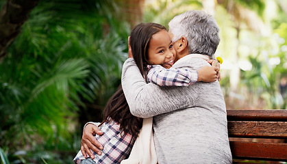 Image showing Happy, young girl and grandmother hug or a flower for senior woman or child with care or bond with pensioner and summer day in the park. Joy, kid and elderly person embrace on the bench with love