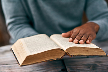 Image showing Hands, faith and a man reading the bible at a table outdoor in the park for religion or belief in god. Book, story and spiritual with a male christian sitting in the garden for study or worship