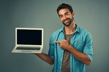 Image showing Happy man, laptop and pointing to mockup screen for advertising or marketing against a grey studio background. Portrait of male person showing computer display or mock up space for advertisement