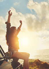 Image showing Road trip, view and arms raised with a woman at the coast, sitting on her car bonnet during travel for freedom or escape. Nature, flare and water with a female tourist traveling in summer at sunset