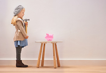 Image showing Waiting, piggy bank and a girl with a hammer for money, savings and finance in a house. Investment, mockup space and little child standing with a tool to break a cash box for coins, banking or wealth