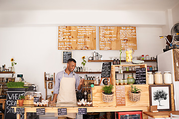 Image showing Black man, coffee shop worker and phone of an entrepreneur with happiness from small business. Cafe, mobile and barista looking on music app for song with smile at bakery and restaurant feeling happy