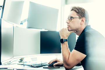 Image showing Stock broker trading online watching charts and data analyses on multiple computer screens.